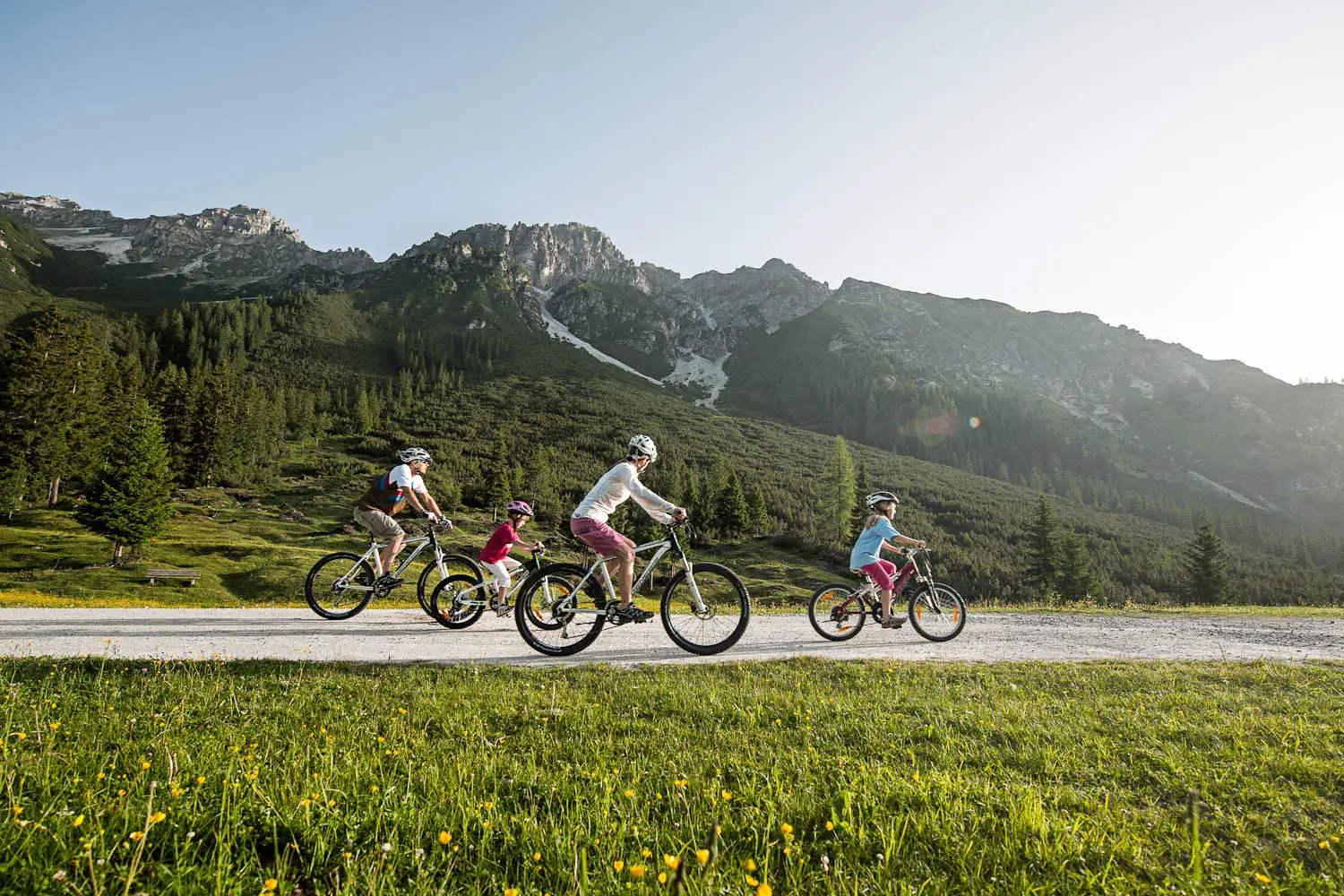 Familie beim Radfahren auf einem Schotterweg vor den Stubaier Bergen