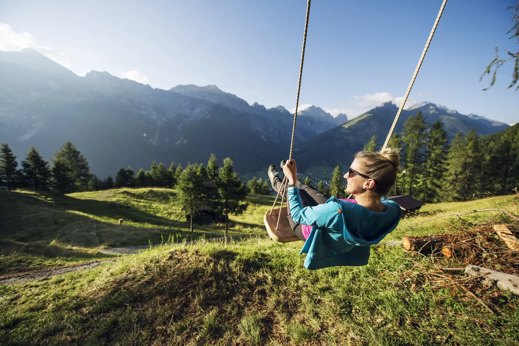 Frau auf einer Schaukel mit Blick auf die Stubaier Berge am Naturschauplatz Gschmitz