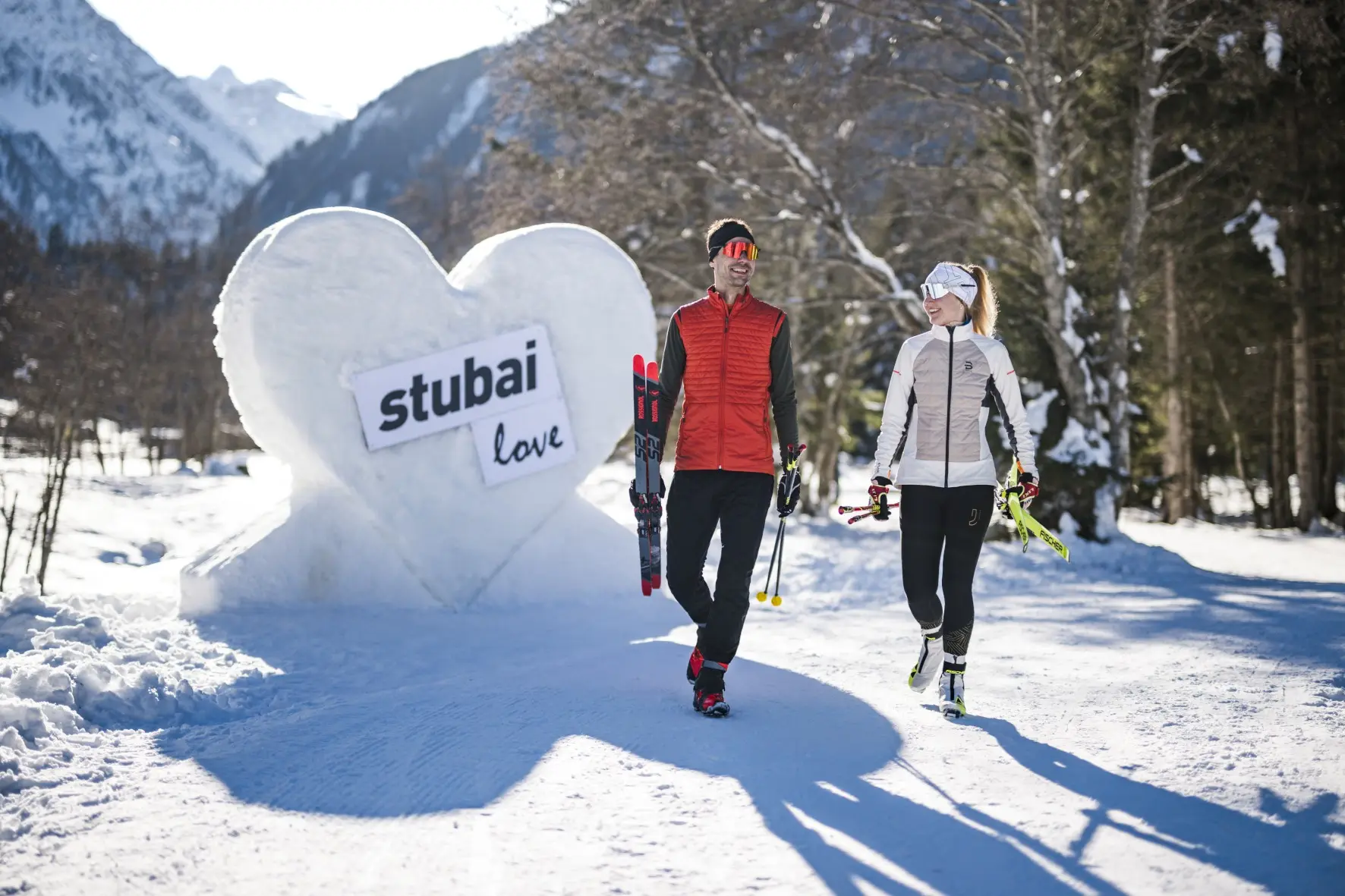Zwei Langläufer neben einem Herz aus Schnee mit Stubai-Logo